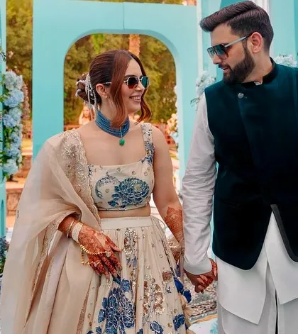A candid moment captured within the elegant blue archway of the Dior-themed Mehendi. The floral arrangements and soft lighting create a romantic and picturesque setting.