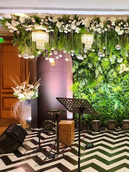 Another angle of the Sangeet stage, showing the musical equipment in place. The combination of the green wall, hanging chandeliers, and patterned floor creates a visually dynamic setting for performers.