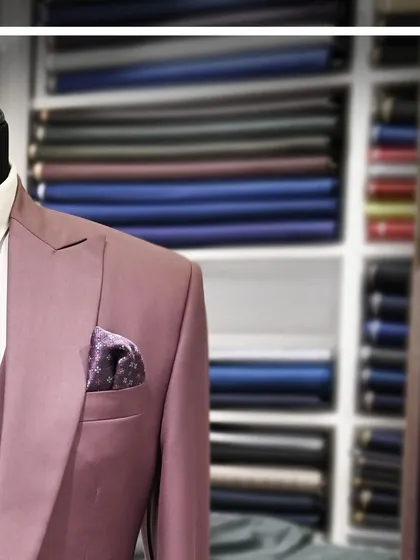 A close-up of the mauve three-piece suit, with the fabric racks in the background, giving a sense of the in-store experience.
