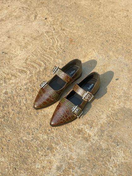 The buckled ballet flat in a unique olive-brown croc finish. This color has a beautiful, subtle variation in tone that makes it a sophisticated and versatile neutral for any season.