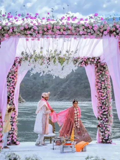 A romantic floral mandap by the river in Rishikesh. The combination of pink flowers and soft drapes against the natural landscape makes for a picturesque and serene wedding ceremony.