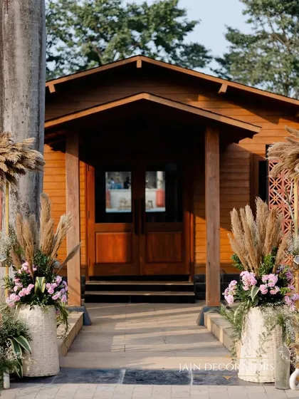 The entrance to a rustic wooden cabin, beautifully decorated with pampas grass and floral arrangements. This shows how I adapt my decor to enhance the natural beauty of a venue.