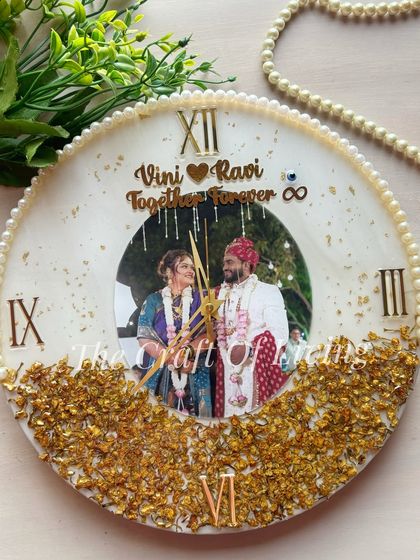 This elegant wall clock features a large wedding photo in the center, with gold flakes creating a sparkling base. The pearl border adds a touch of classic sophistication.