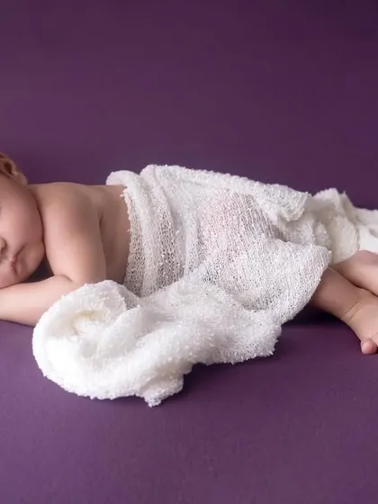 A beautifully simple pose, with the newborn wrapped loosely in white gauze. This minimalist approach keeps the focus on your baby's natural and peaceful state.