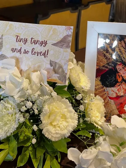 A personal touch on a tabletop, with a framed photo of the couple alongside a custom-printed card and fresh flowers.