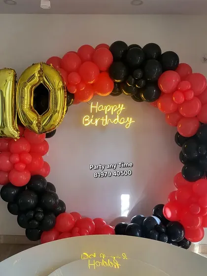 A red and black circular balloon arch for a 10th birthday.