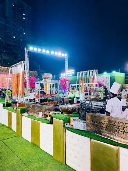A bustling scene at the modern catering counters, with chefs serving guests and smoke rising from the live grills.