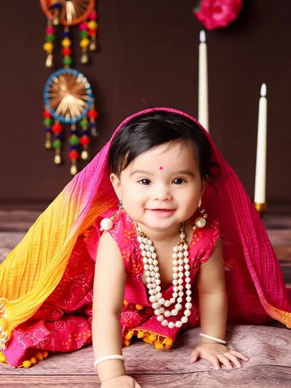A full-length view of the traditional setup, featuring colorful dreamcatchers and floral garlands that complement the baby's vibrant outfit.