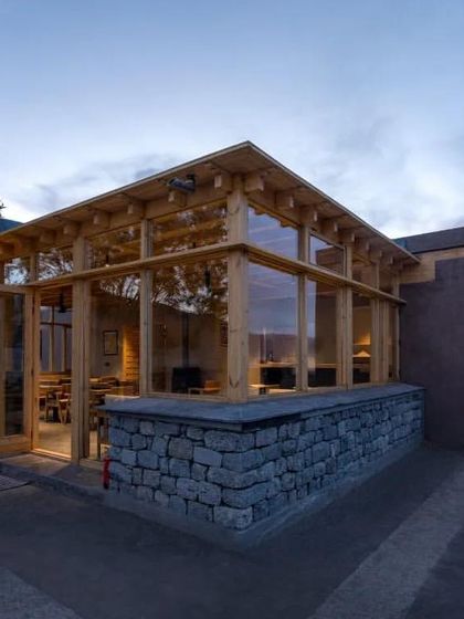Another exterior shot of the Postcard hotel, highlighting its simple, elegant form. The structure is built with local stone and wood, grounding it in the region's vernacular building traditions.