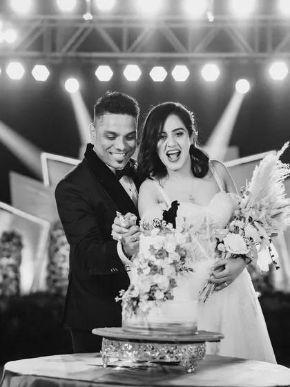 A candid black and white shot of the cake cutting. The bride's joyful, open-mouthed laugh makes this a wonderfully authentic moment.
