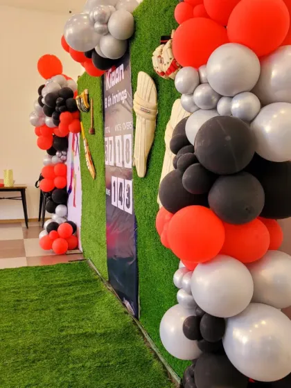 This side view shows the depth of the balloon garland and how it frames the cricket-themed wall.