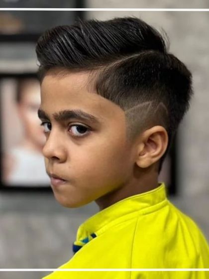 A young boy with a trendy haircut featuring a sharp side part and a creative design shaved into the side.