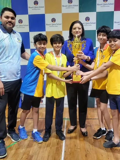 Our winning boys' team and their coach holding the championship trophy at the inter-school tournament.