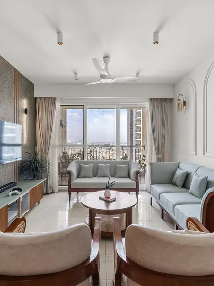 This wide shot of a compact living room at Shapoorji Pallonji Parkwest shows how smart design can maximize space. The light blue sofas and large window create an open, airy feel, while the custom wooden furniture adds warmth and character.