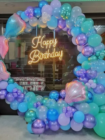 An enchanting mermaid-themed balloon ring. The decoration uses shades of aqua, purple, and blue, with shell and mermaid tail foil balloons to complete the underwater look.