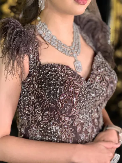 This deep brown, fish-cut gown with feather details is perfect for a bold and dramatic evening look.