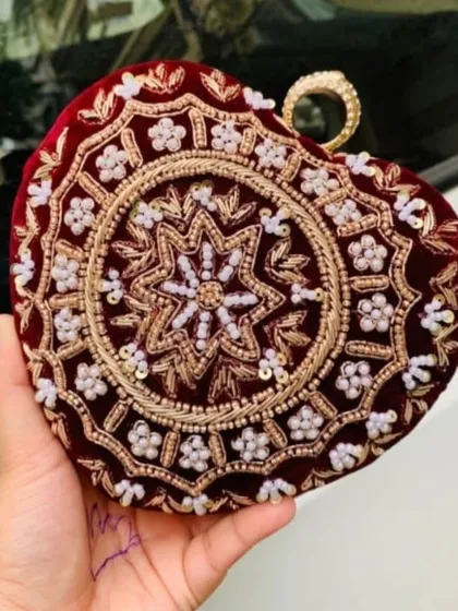 This heart-shaped clutch in deep red velvet shows the intricate beadwork and embroidery I do. Even without names, the detailed craftsmanship makes it a stunning bridal accessory.