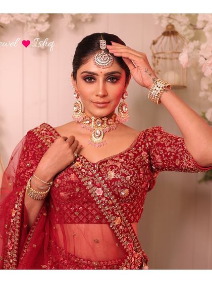 A bride looking regal in a red lehenga, complemented by a beautiful Polki choker with pastel pink bead drops and matching oversized earrings.
