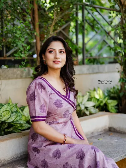 A serene outdoor portrait. The actress is seated on a bench in a lovely purple dress, her pensive expression creating a calm and thoughtful mood.