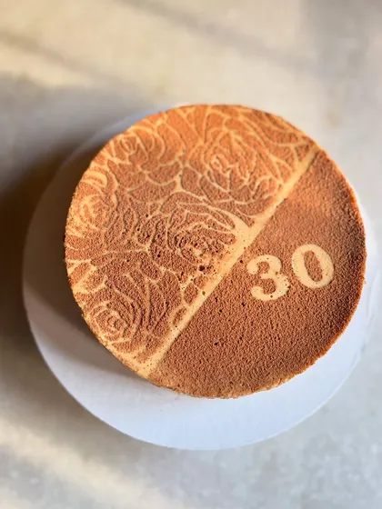 This is my bestseller for a reason: the boozy coffee baked yogurt cake. It's creamy, addictive, and a bit lighter than a traditional cheesecake. I can customize the top with stencils for any occasion, like this 30th birthday celebration.