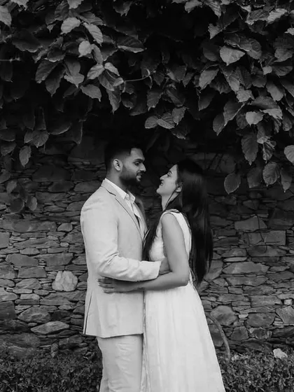 A classic, romantic pose under a canopy of leaves. This black and white photo has a timeless and intimate feel.