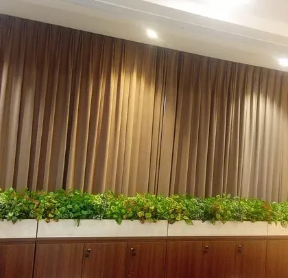 A long planter box filled with lush, low-profile artificial greenery, placed on top of cabinets in an office or boardroom to add a touch of nature.