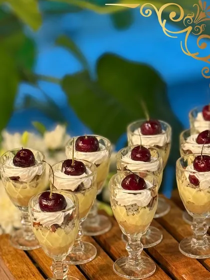 Every meal deserves a sweet ending. These individual dessert glasses are layered with cream and cake, and topped with a fresh cherry, offering an elegant and indulgent bite for your guests.
