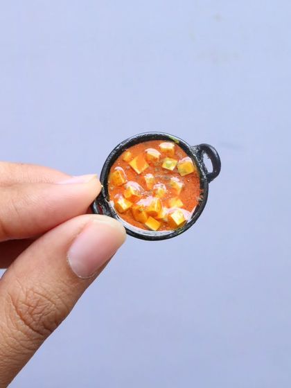 A single, perfect miniature of paneer butter masala in a tiny kadai.