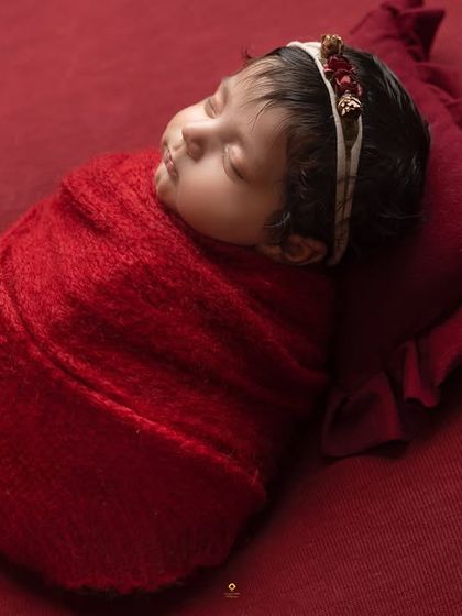 A side-profile of a baby wrapped in red, resting on a matching pillow. This angle is perfect for capturing the delicate curve of their cheek and lips.