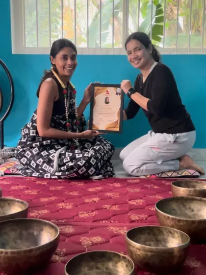 A student receives her certificate for completing the Singing Bowl & Sound Healing Teacher Training Course, a testament to her hard work.