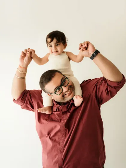 A proud dad gives his little one a shoulder ride. This is a fun and classic pose for a father and child photoshoot.