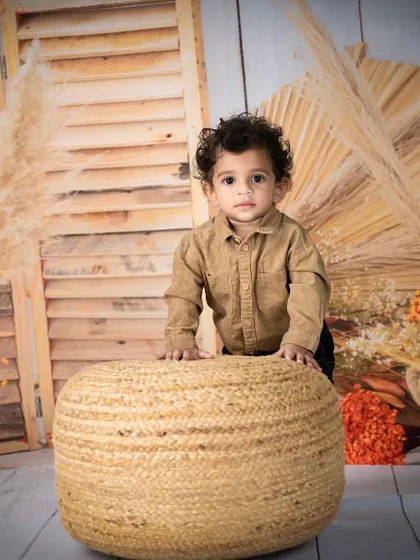 A handsome little boy in a rustic, autumn-themed setup. The warm tones and natural textures create a cozy and stylish portrait.