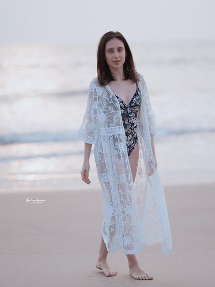 A full-body shot showing the model walking along the shore. This type of image is perfect for showcasing resort wear in its natural environment.