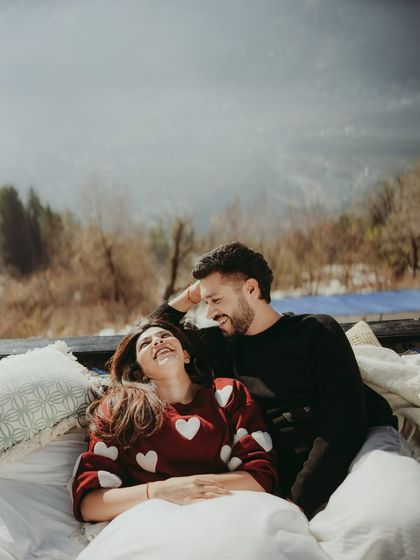 Laughter and love on a comfy outdoor bed setup, with the beautiful mountains of Manali in the background.