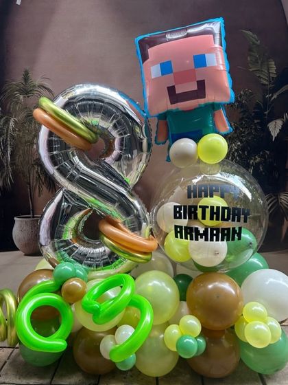 A Minecraft-themed balloon bouquet for an 8th birthday. Featuring a Steve foil balloon, a large number 8, and a personalized bubble balloon, it's the perfect gift for any young gamer.