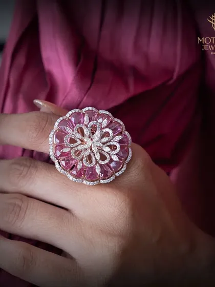 A floral fantasy in pink. This large cocktail ring is crafted with intricately carved pink gemstones forming petals around a diamond center, creating a beautiful, blooming effect.