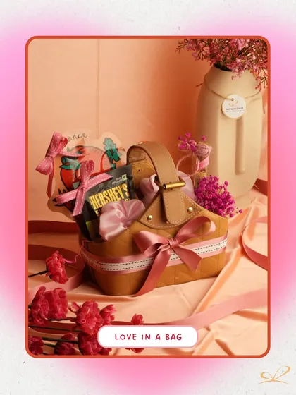 'Love in a Bag' is a uniquely shaped hamper that looks like a chic handbag. It's filled with Hershey's chocolates, skincare items, and decorated with pink ribbons, combining style and sweetness.