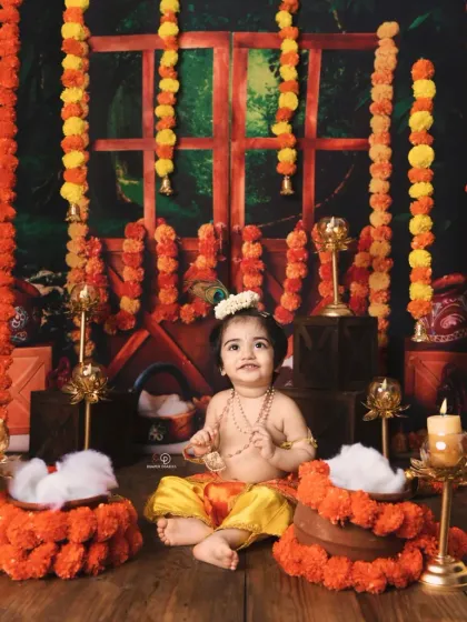A beautiful and traditional 'Kanha' themed shoot for Janmashtami. The baby is dressed as Lord Krishna, set against a backdrop of marigold garlands and brass lamps.