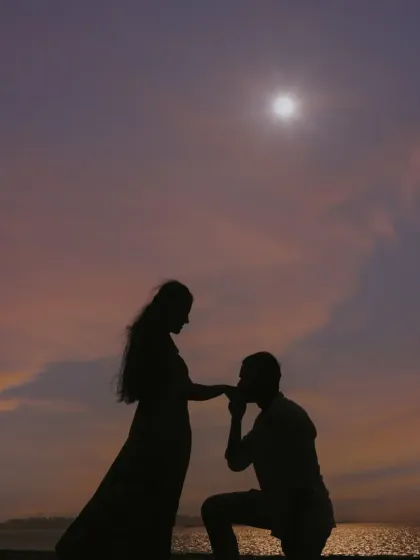 A classic pre-wedding proposal silhouette against a beautiful sunset sky, capturing a timeless and romantic moment.