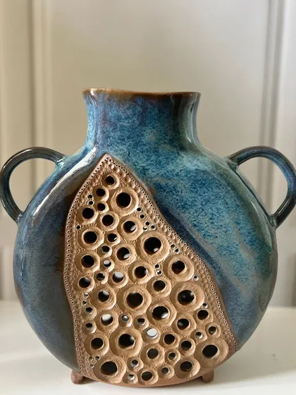 This large, slab-built vase features a unique carved and pierced design. The contrast between the raw, unglazed carved section and the glossy blue glaze creates a wonderful texture and visual interest.