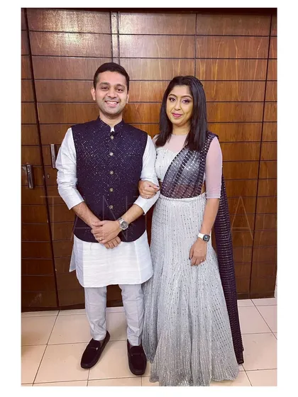 I love creating coordinated looks for couples. Here, we have a custom-made embellished Bundi jacket and raw silk kurta set for him, perfectly complementing her stunning glitter net fish-cut lehenga with an attached dupatta.