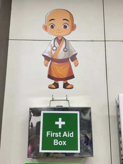 Even a first aid box can be part of the design. Here, a cute monk-as-a-doctor mural is placed just above the box, turning a mandatory safety feature into a charming and playful detail on the factory wall.