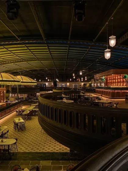 The sweeping curve of the mezzanine balcony, a key architectural feature that defines the space. This element helps to create a dynamic visual flow and offers varied perspectives of the bar below.