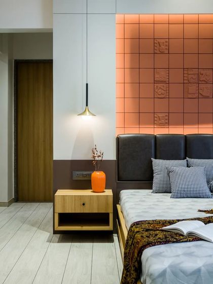 A bedroom in the 'Yashodanand' residence features a unique headboard made of terracotta tiles with embossed patterns, adding texture and warmth to the space.