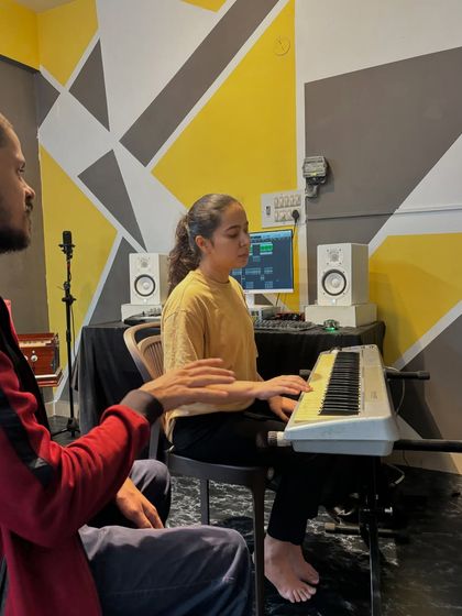 An instructor offers gentle guidance and correction to a student during her keyboard lesson, ensuring she develops the correct hand posture and technique.