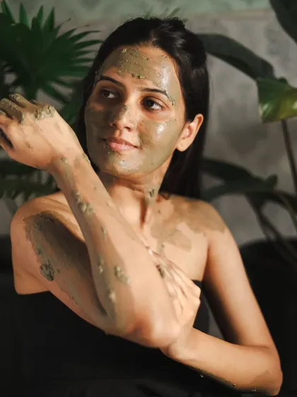 This shot captures a different angle, showing the application of the Ayurvedic clay. It's a great image for a skincare brand or a wellness-themed editorial.