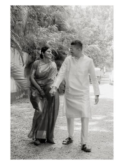 A black and white photo of a couple walking hand-in-hand. This timeless shot emphasizes the connection between them, with the natural surroundings creating a soft background.