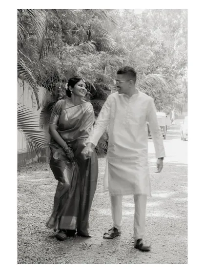 A black and white photo of a couple walking hand-in-hand. This timeless shot emphasizes the connection between them, with the natural surroundings creating a soft background.