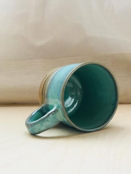 The Flow Mug on its side, showcasing its sturdy handle and the beautiful gradient of the glaze.