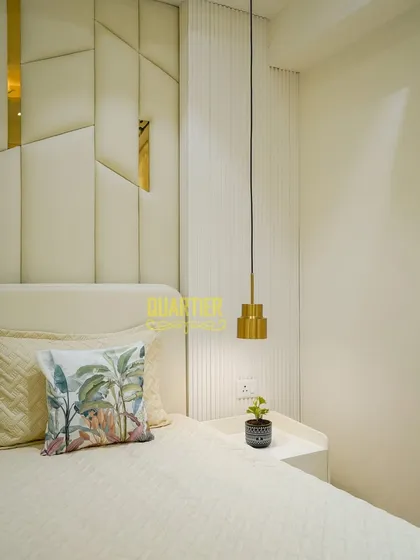 A close-up of the master bedroom at Tata LaVida, highlighting the textures. The padded headboard, vertical fluted paneling, and the sleek pendant light come together to create a space that is both visually interesting and deeply calming.